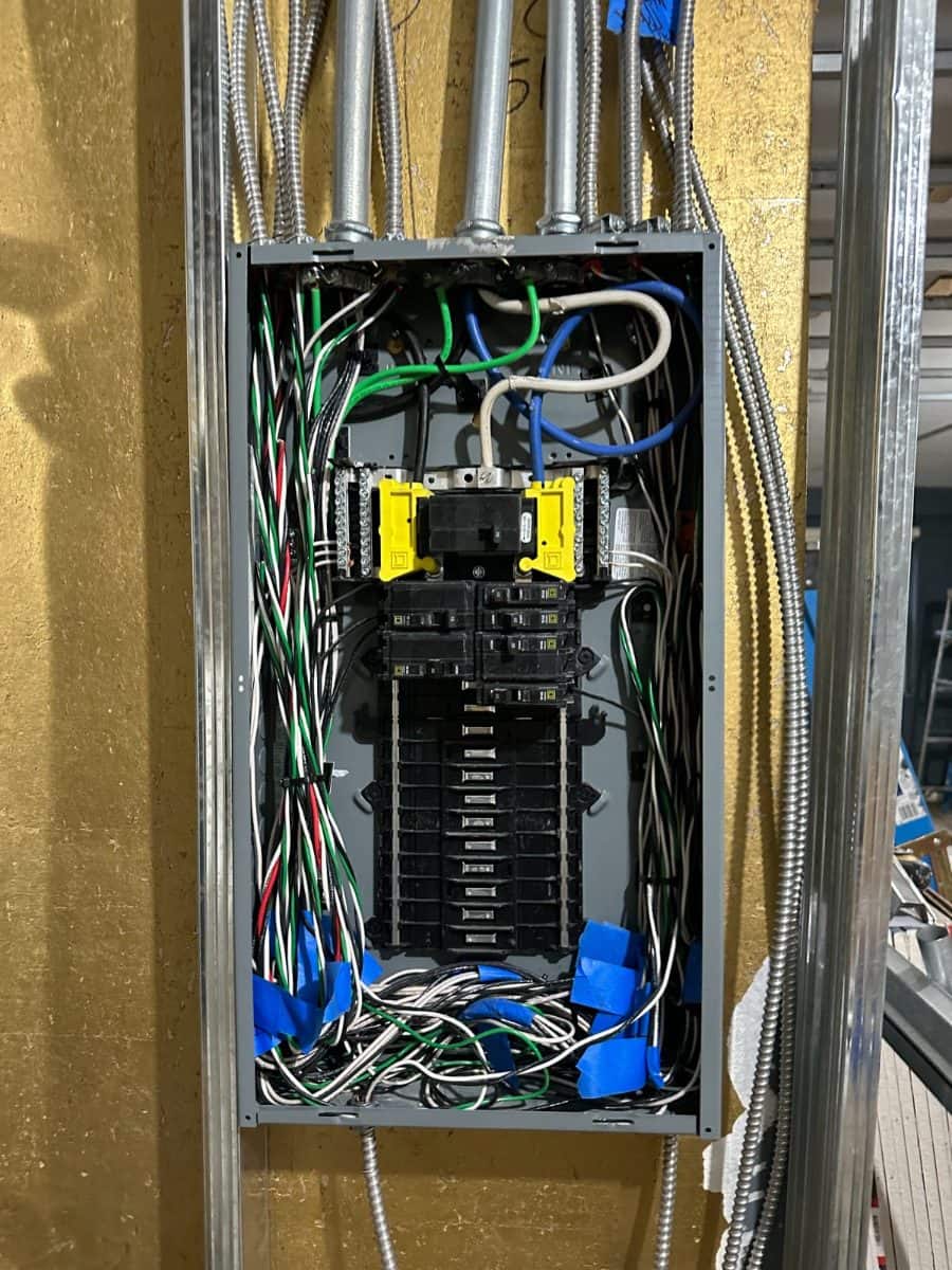 Electrical panel relocated during construction, with conduit runs stubbed into the wall